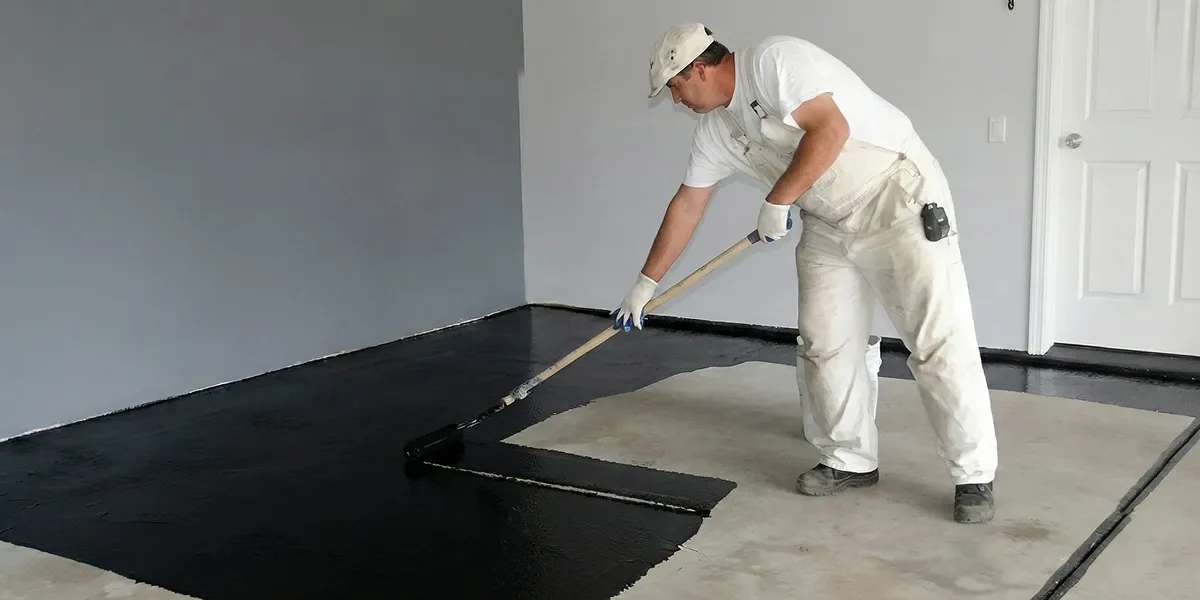 basement waterproofing professional applying waterproof coating to protect a basement floor in Baton Rouge, LA